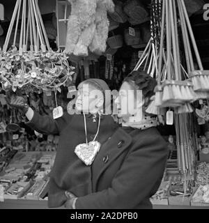 Ein kleiner Junge mit dem Arm seiner Mutter bin Spielzeugstand auf dem Weihnachtsmarkt, Deutschland 1930er Jahre. Einen kleinen Jungen in den Armen seiner Mutter an der Spielzeug Stand des Weihnachtsmarktes, Deutschland 1930. Stockfoto