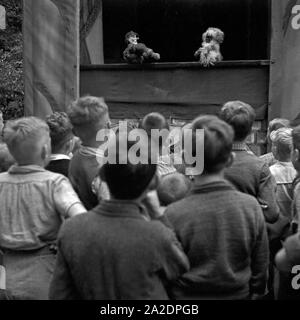 Großer Spaß für die Kleinen: eine Aufführung in einem Kasperltheater auf der Festwiese in Berlin Stralau, Deutschland 1930er Jahre. Großer Spaß für die Kleinen: ein Kasperletheater am Berlin Stralau jährliche Messe, Deutschland 1930. Stockfoto