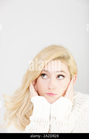 Schöne junge Frau, die ihr Kinn auf ihre Hände ruhen verärgert Stockfoto