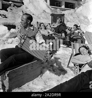 Ein Angesteller des Feldbergerhof Hotels unterhält Sterben dösenden Feriengäste beim Sonnenbad mit Schwarzwaldmelodien, Deutschland 1930er Jahre. Ein Mitarbeiter der Feldberghof Hotel unterhalten die Gäste mit Schwarzwald Tunes, Deutschland 1930. Stockfoto