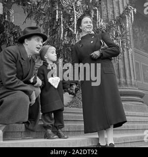 Ein kleiner Junge mit-Eltern auf den Stufen vor dem Weihnachtsbaum am Berliner Dom, Deutschland 1930er Jahre. Ein kleiner Junge mit seinen Eltern auf den Stufen des Berliner Doms vor einem Weihnachtsbaum, Deutschland 1930. Stockfoto