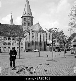 Ein Mann sterben füttert Tauben auf dem Platz vor der Stiftskirche St. Martin und St. Maria in Kaiserslautern, Deutschland 1930er Jahre. Ein Mann Fütterung pigions auf dem Platz vor St. Martin und St. Mary's Stiftskirche in Kaiserslautern, Deutschland 1930. Stockfoto