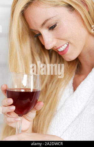 Schöne junge Frau in einem weißen Gewand, ein Glas Rotwein Stockfoto