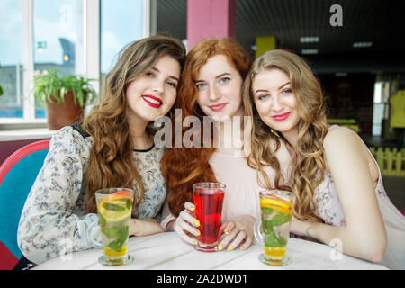 Drei lächelnde Frauen sitzen in einem Café. Freundschaft, Begegnung und Lifestyle Konzept. Stockfoto