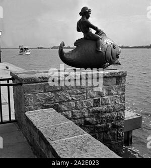 Der Putto mit dem Fisch, eine Skulptur des Künstlers Hermann Scheuernstuhl, am Ufer des Maschsees in Hannover, Deutschland 1930er Jahre. Putto reiten auf einem Fisch, eine Skulptur von Hermann Scheuernstuhl, am Ufer des künstlichen Maschsee in Hannover, Deutschland 1930. Stockfoto