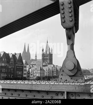 Altstadt von Köln mit Dom und Groß St. Martin Sterben, durch einen Aufhänger der Hindenburgbrücke gesehen, 1930er Jahre. Alte Stadt Köln mit Dom und St. Martin Kirche, die durch die Drähte der alte Hindenburg Brücke gesehen, 1930er Jahre. Stockfoto