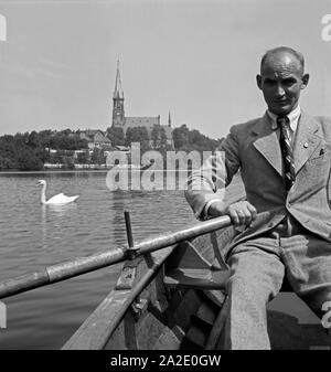 Ein Mann in einem Ruderboot mit dem Schloßteich in Chemnitz, Deutschland 1930er Jahre. Ein Mann Rudern mit dem Boot auf dem Schlossteich in Chemnitz, Deutschland 1930. Stockfoto