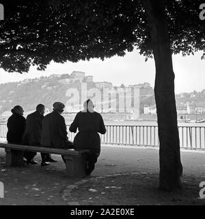 Menschen Artikel am Rheinufer und schulmeisterschaft in der Festung Ehrenbreitstein bei Koblenz sterben, Deutschland 1930er Jahre. Leute sitzen am Ufer des Rheins und beobachten die Festung Ehrenbreitstein bei Koblenz, Deutschland 1930. Stockfoto