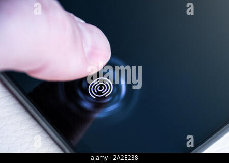 Unlocking the phone with the finger on a digital fingerprint scanner built in under the screen close up Stockfoto