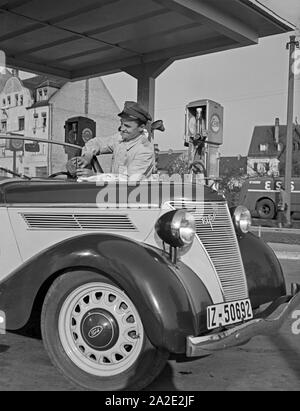 Der freundliche Tankwart an der Esso Tankstelle wischt sterben Windschutzscheibe, Deutschland 1930er Jahre. Freundliche Tankstelle attendant Reinigung der vorderen Schutzplatte, Deutschland 1930. Stockfoto