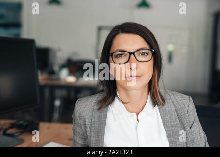 Zuversichtlich geschäftsfrau an ihrem Schreibtisch sitzen in einem Büro Stockfoto