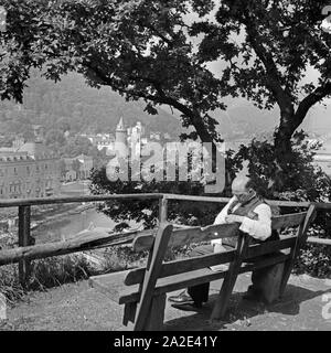 Ein Mann sitzt lesend auf einer Bank am Ufer der Lahn in Bad Ems, Deutschland 1930er Jahre. Ein Mann Lesung auf einer Bank in Bad Ems, Deutschland 1930. Stockfoto