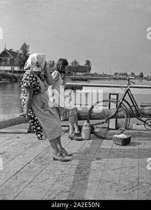 Eine Frau und ein Mädchen auf der Fähre über den induktionskopfhörern Nemonien im Memeldelta, Ostpreueßn, 1930er Jahre. Eine Frau und ein Mädchen auf der Fähre auf dem Fluss Memel Nemonien im Delta, Ostpreußen, 1930er Jahre. Stockfoto