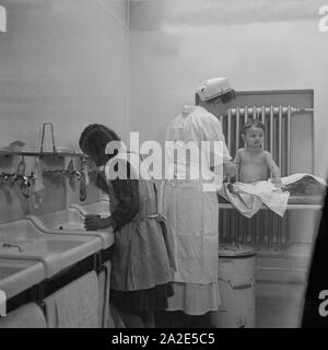 Eine Krankenschwester hilft Kindern beim Waschen im Mütterheim Dresden in Schloß Dittersbach, Deutschland 1930er Jahre. Eine Krankenschwester hilft die Kinder waschen bei den Rest Zentrum für Mütter in Dittersbach Castle in der Nähe von Dresden, Deutschland 1930. Stockfoto