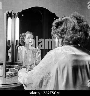 Schwedische Fictitious character und Sängerin Zarah Leander schminkt sich vor dem Spiegel in ihrem Haus in Berlin, Deutschland, 1930er Jahre. Schwedische Sängerin und Schauspielerin Zarah Leander das Make up vor einem Spiegel in ihrem Haus in Berlin, Deutschland 1930. Stockfoto