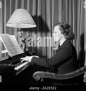 Die schwedische Fictitious character und Sängerin Zarah Leander spielt mit dem Cembalo in ihrem Haus in Berlin, Deutschland, 1930er Jahre. Schwedische Sängerin und Schauspielerin Zarah Leander spielen auf dem Cembalo an ihrem Haus in Berlin, Deutschland 1930. Stockfoto