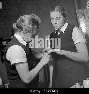 Zwei Frauen bei der Ersten Hilfe bei einem kleinen Haushaltsunfall beim weiblichen Arbeitsdienst in Molkenberg bei Fürstenwalde, Deutschland 1930er Jahre. Zwei Frauen an einem Erste Hilfe von einem kleinen Ordnung und Sauberkeit Katastrophe an die weibliche belegschaft Gruppe von Molkenberg, Deutschland 1930. Stockfoto