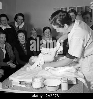 Frauen lernen Windelwechsel bei einer Mütterschulung des Reichsmütterdienstes in Essen teil, Deutschland 1930er Jahre. Frauen erfahren Sie, wie Sie die Windeln des Babys auf eine Mutter Ausbildung der Reichsmuetterdienst in Essen, Deutschland 1930 s zu ändern. Stockfoto