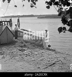 Ein Mann und eine Frau bringen Ein KLEPPER Faltboot zu Wasser, Deutschland 1930er Jahre. Ein Mann und eine Frau, eine KLEPPER Faltboot in das Wasser, Deutschland 1930. Stockfoto