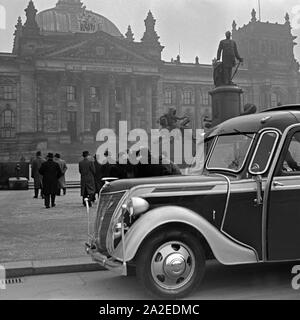 Eine Reisegruppe in ihrem Bus vor dem Reichstagsgebäude in Berlin, Deutschland, 1930er Jahre. Eine Gruppe von Reisenden mit ihrem Trainer vor dem Reichstag, Deutschland 1930. Stockfoto