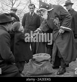 HoHoHo! Ein kleiner Junge drückt auf dem Weihnachtsmarkt mit dem Weihnachtsmann sterben Hand, Deutschland 1930er Jahre. Ein kleiner Junge und Santa Claus Händeschütteln auf dem Weihnachtsmarkt, Deutschland 1930. Stockfoto