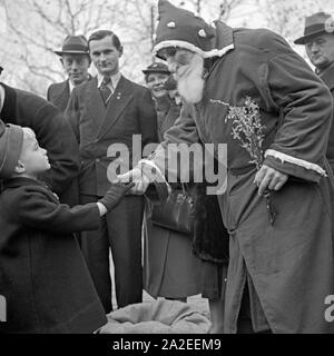 Ein kleiner Junge schüttelt ganz ernst dem Weihnachtsmann sterben Hand auf dem Weihnachtsmarkt, Deutschland 1930er Jahre. Ein kleiner Junge und Santa Claus Händeschütteln auf dem Weihnachtsmarkt, Deutschland 1930. Stockfoto