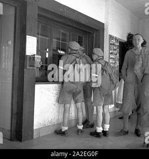 Drei frisch angekommene Hitlerjungen bei der Anmeldung der Adolf Hitler die Jugendherberge in Berchtesgaden, Deutschland 1930er Jahre. Drei Hitler Jugend an der Rezeption des Adolf Hitler Youth Hostel in Berchtesgaden, Deutschland 1930. Stockfoto