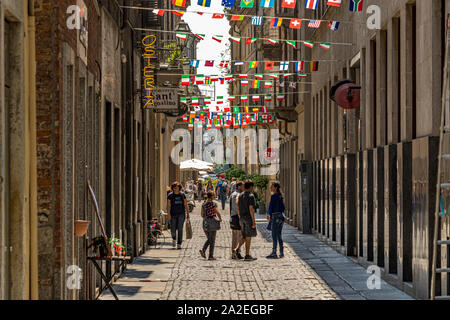 Eine Gruppe von Menschen zu Fuß entlang der Via Sant'Agostino, einem schmalen Seitenstraße mit kleinen Flaggen, Turin, Italien eingerichtet Stockfoto