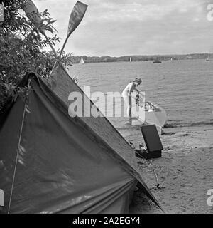 Werbefoto für KLEPPER Faltboot und Zelt: eine junge Frau holt ein Boot am Strand eines sieht ein Land, Deutschland 1930er Jahre. Werbung für ein Klepper foldboat und Zelt: Eine junge Frau, die ein Boot am Ufer eines Sees, Deutschland 1930. Stockfoto