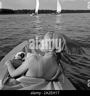 Werbefoto für KLEPPER Faltboot: eine junge Frau paddelt mit einem Welpen in einem Sehen, Deutschland 1930er Jahre. Werbung für ein Klepper foldboat: eine junge Frau mit einem Welpen paddeln auf einem See, Deutschland 1930. Stockfoto