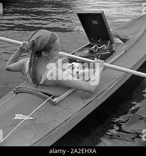 Werbefoto für KLEPPER Faltboot: eine junge Frau paddelt mit einem Welpen in einem Sehen, Deutschland 1930er Jahre. Werbung für ein Klepper foldboat: eine junge Frau mit einem Welpen paddeln auf einem See, Deutschland 1930. Stockfoto