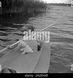 Werbefoto für KLEPPER Faltboot: eine junge Frau paddelt mit einem Welpen in einem Sehen, Deutschland 1930er Jahre. Werbung für ein Klepper foldboat: eine junge Frau mit einem Welpen paddeln auf einem See, Deutschland 1930. Stockfoto