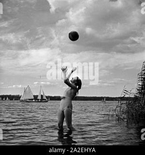 Werbefoto: eine junge Frau spielt mit einem Wasserball am Strand eines sieht, Deutschland 1930er Jahre. Werbung: eine junge Frau spielen Wasserball am Strand, Deutschland 1930. Stockfoto