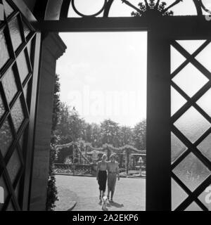 Zwei Frauen und ein Foxterrier von einems Portal der Villa Berg in Stuttgart aus gesehen, Deutschland 1930er Jahre. Zwei Frauen mit einem Fox Terrier, von einer Tür der Villa Berg Mansion at Stuttgart, Deutschland der 1930er Jahre gesehen. Stockfoto