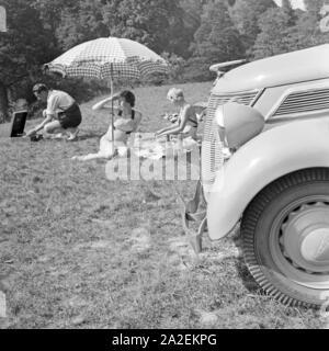 Ein Mann und zwei Frauen beim Picknick vor einem Ford V6, Deutschland 1930er Jahre. Ein junger Mann und zwei Frauen in ein Pick Nick vor einem Ford V8, Deutschland 1930. Stockfoto