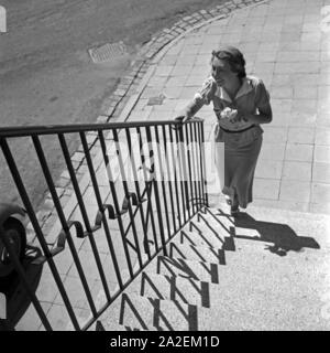 Eine Frau mit einem Blumenstrauß ein einer Treppe in der Innenstadt von Stuttgart, Deutschland 1930er Jahre. Eine junge Frau mit Blumen an einer Treppe in der Innenstadt von Stuttgart, Deutschland 1930. Stockfoto