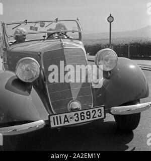 Zwei Frauen und ein Mann unterwegs in einem Mercedes Benz Cabrio, Deutschland 1930er Jahre. Zwei Frauen und ein Mann auf dem Weg in ein Mercedes Benz Cabrio, Deutschland 1930. Stockfoto