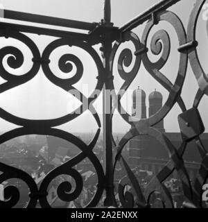 Blick auf die Frauenkirche in München vom Turm der Kirche St. Peter, Deutschland 1930er Jahre. Blick auf die Münchner Frauenkirche durch das Geländer der Glockenturm der Kirche St. Peter, Deutschland 1930. Stockfoto