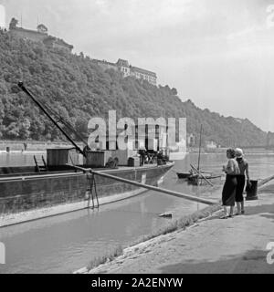 Zwei Frauen am Ufer der Donau in Passau mit Blick auf die Veste Oberhaus, Deutschland 1930er Jahre. Zwei Frauen am Ufer der Donau bei Passau mit Blick auf die Burg Oberhaus, Deutschland 1930. Stockfoto