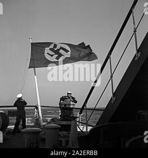 Matrosen steuern mein Schiff unter der Reichsflagge, Deutschland 1930er Jahre. Segler Lenkung ein Schiff unter der Hakenkreuzflagge, Deutschland 1930. Stockfoto