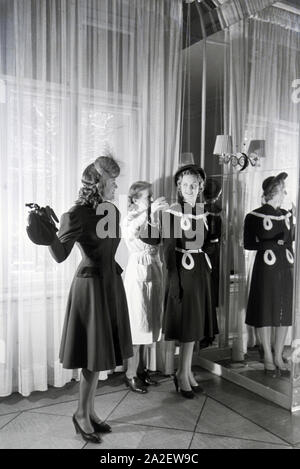 Zwei Modelle und eine Schneiderin bei der Anprobe von Kleidern von Modeschöpferin Annemaria Geise; Deutschland Ca. 1939. Zwei Modelle und eine maßgeschneiderte versuchen, Kleider Mode Designer Annemaria Geise; Deutschland Ca. 1939. Stockfoto