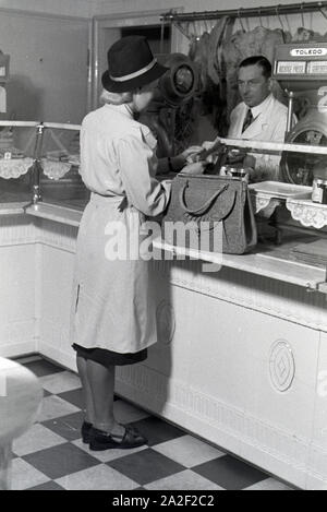 Eine Kundin beim Einkauf im Musterbetrieb Wilhelm Plum in München Gladbach, Deutsches Reich 1941. Ein client Shopping in der Modellpflanze Wilhelm Plum in Stockfoto