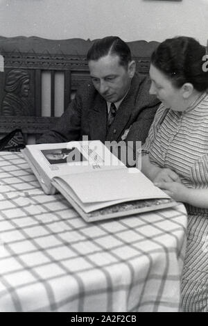 Die Inhaber des Musterbetriebs Wilhelm Pflaume mit einem Fotoalbum, Deutsches Reich 1941. Eigentümer der Modellpflanze Wilhelm Pflaume mit einem Fotoalbum, Deutschland 1941. Stockfoto