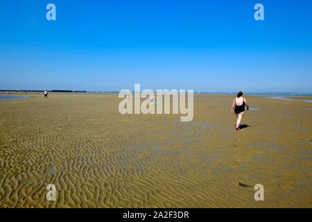 Ein Schwimmer zu Fuß auf das Meer und eine Familie spielen Beach Cricket auf Ryde Sandbänken bei Ebbe Blick in den Solent Stockfoto