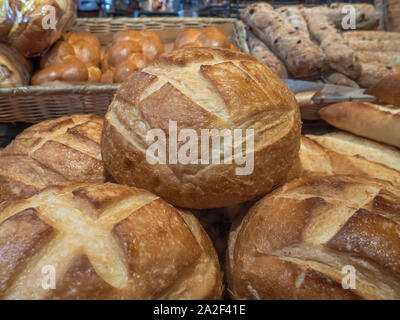 In der Nähe von frisch gebackenen runden Laibe Brot in einem Markt Anzeige an einer Bäckerei mit anderen Arten von Brot im Hintergrund gestapelt. Stockfoto