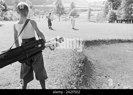 Tennisspieler bei einer Partie auf dem Spielfeld und ihr Publikum, Freudenstadt, Deutschland 1930er Jahre. Tennis Spieler bei einem Match auf dem Tennisplatz und ihrem Publikum, Freudenstadt, Deutschland 1930. Stockfoto