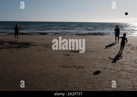 Compton Strand bei Ebbe am späten Nachmittag Sommer Sonnenschein und eine Familie treten ein Fußball auf dem Sand Stockfoto