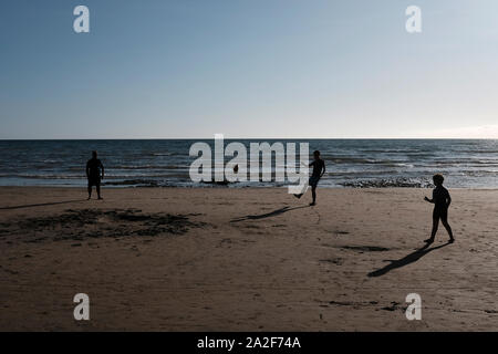 Compton Strand bei Ebbe am späten Nachmittag Sommer Sonnenschein und eine Familie treten ein Fußball auf dem Sand Stockfoto