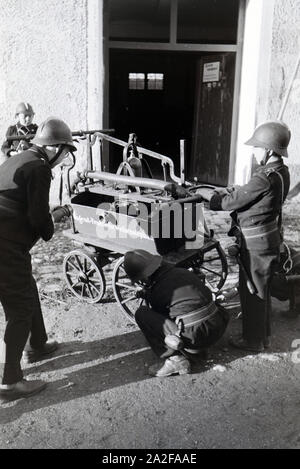 Eine Gruppe von der Kinderfeuerwehr mit dem Löschwagen bei einer Feuerwehrübung, Deutschland 1930er Jahre. Eine Gruppe von Junior Feuerwehrmänner ist die Vorbereitung der firewagon während ein Feuerwehrmann, Deutschland 1930. Stockfoto