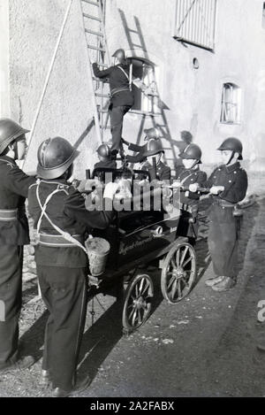 Eine Gruppe von der Kinderfeuerwehr mit dem Löschwagen und der Projektleiter bei einer Feuerwehrübung, Deutschland 1930er Jahre. Eine Gruppe von Junior Feuerwehrmänner ist die Vorbereitung der firewagon und Leiter während ein Feuerwehrmann, Deutschland 1930. Stockfoto